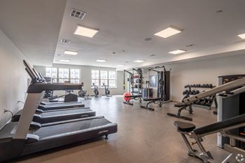 a gym with treadmills and other exercise equipment and windows